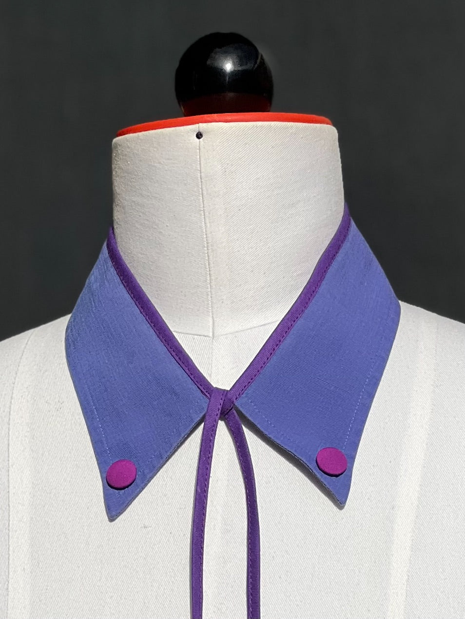 Detail: stoffbezogene Magenta-Knöpfe an den Spitzen des lavendelblauen Kragens