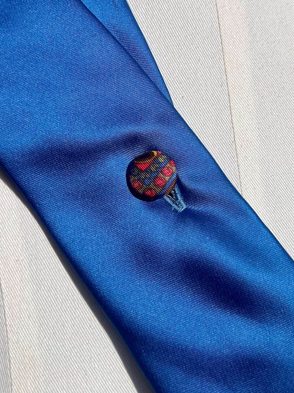 Detail: bunter Vintage-Stoffknopf in Rot und Gold auf kobaltblauer Seide