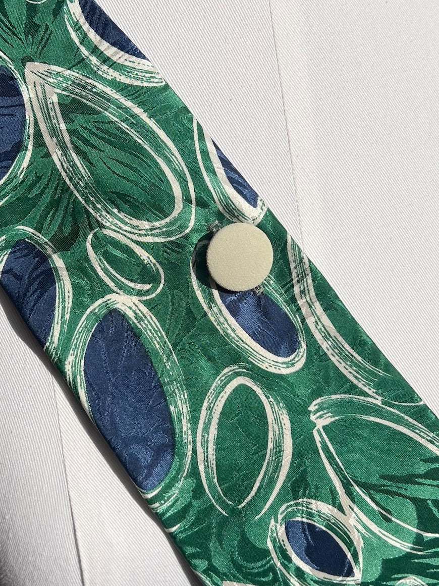Detail: cremefarbener Vintage-Knopf auf grün-blauer Seide