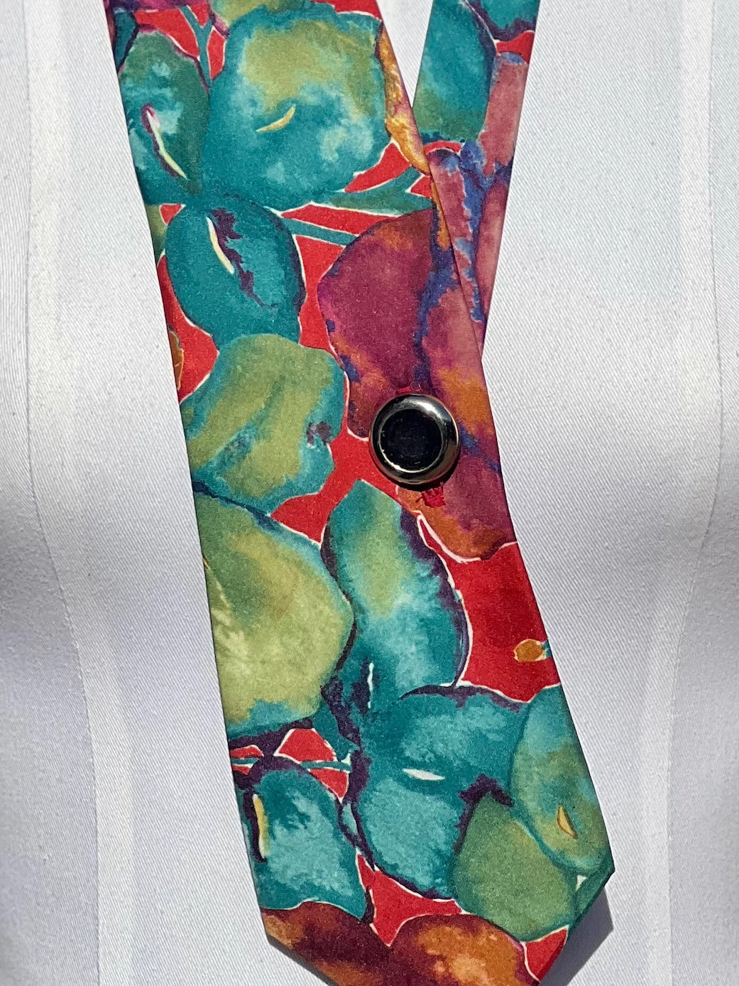 Detail: alter Knopf mit Silberrand auf bunter Batikseide