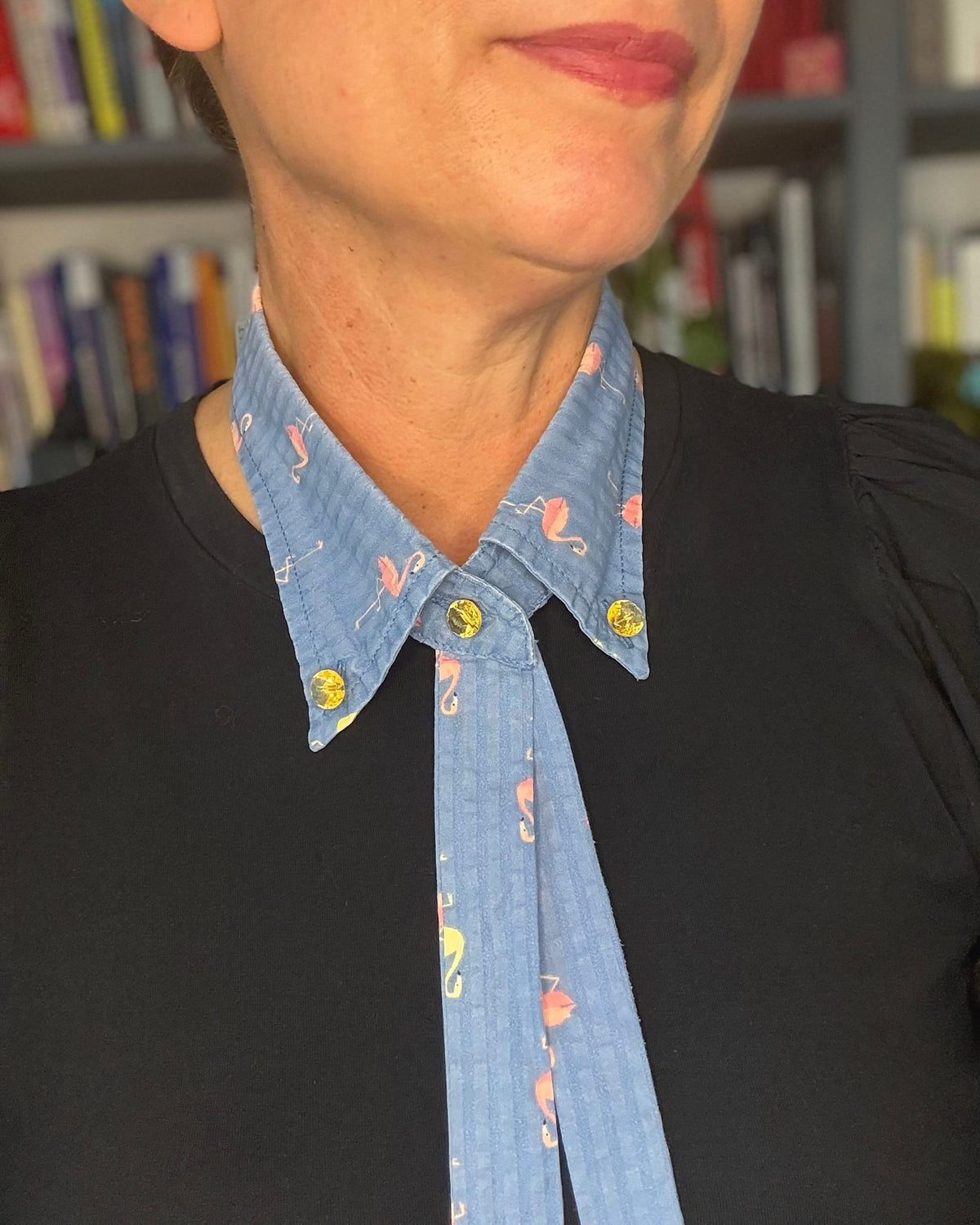 Kragencollier Flamingo getragen zu schwarzem Shirt, Bänder lang herabhängend, goldene Glasknöpfe