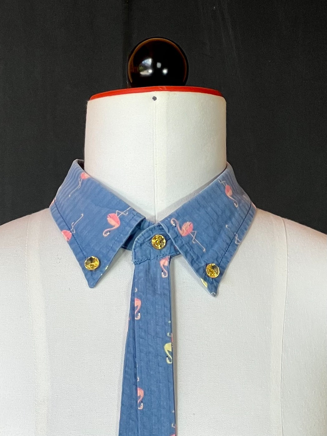 Detail: goldene Vintage-Glasknöpfe am zartblauen Flamingo-Kragen
