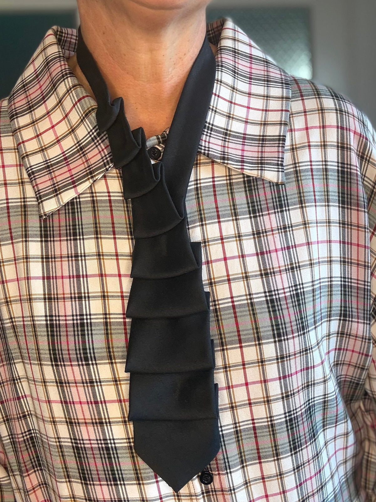Schlipscollier Noir Attitude getragen zu karierter Bluse, schwarze Lagen gestuft wie ein Jabot