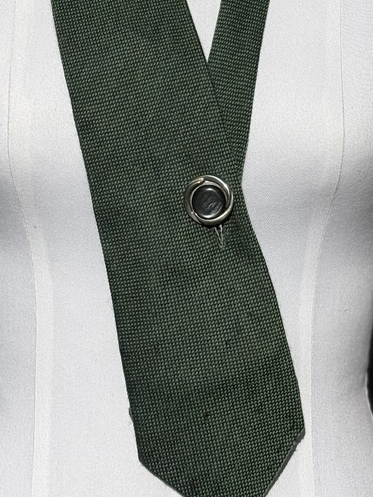 Detail: silberner Vintage-Knopf auf dunkelgrünem Strukturstoff