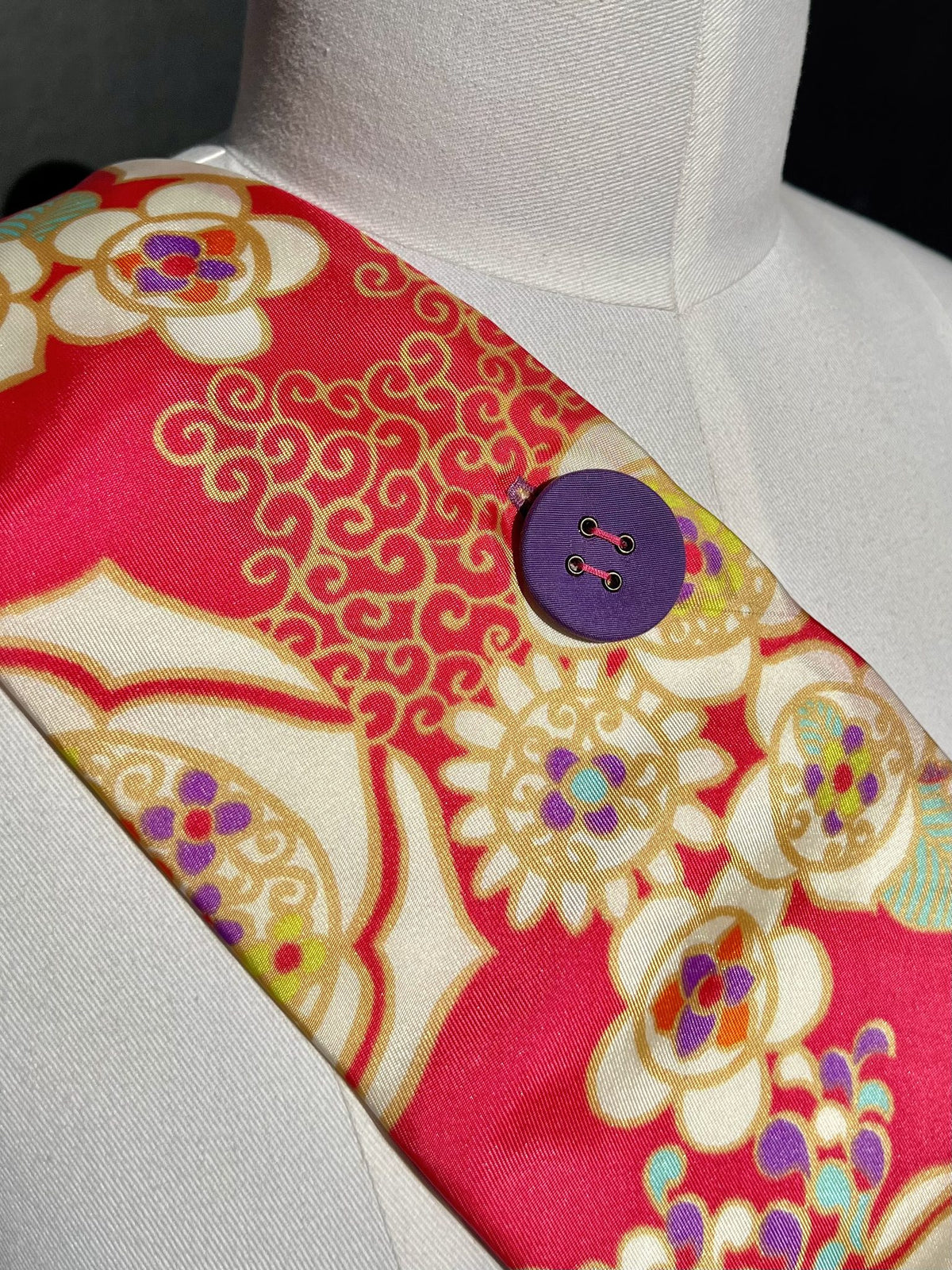 Detail: lila Knopf auf pinkem Blütenmuster mit goldenen Ranken